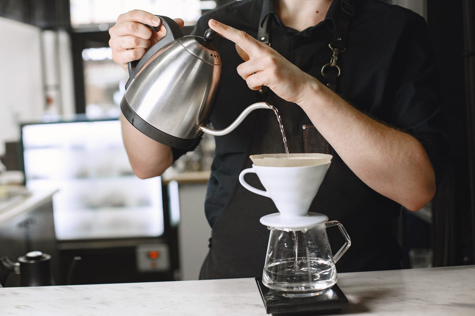 Barista preparando café em jarra de vidro pelo método coado